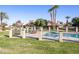 Fenced in Community pool surrounded by green grass and mature trees at 943 E Kortsen Rd # 2, Casa Grande, AZ 85122