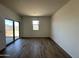 Bright living room with wood look flooring, neutral walls, and sliding glass doors to the backyard at 11796 N Vanero Ct, Maricopa, AZ 85139