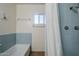 Bathroom featuring light blue tiles, a window, and a shower with a white curtain and silver fixtures at 120 S Olive --, Mesa, AZ 85204