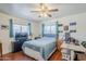 Bedroom featuring hardwood floors, a blue bedspread, two windows with blue curtains, a tv, and a desk at 120 S Olive --, Mesa, AZ 85204