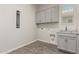 Bright laundry room featuring gray cabinets, wood-look tile flooring, and laundry-themed decor at 1228 W Snowbell Ave, Queen Creek, AZ 85140