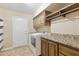 Practical laundry room with washer, dryer, storage cabinets, and granite countertop at 12748 N 57Th Dr, Glendale, AZ 85304