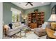 Comfortable living room with plush sofa, bookshelves, ceiling fan, and a large window at 12904 W Dale Ln, Peoria, AZ 85383
