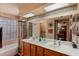 Bathroom featuring dual sinks, decorative mirrors, a shower over tub, and patterned wallpaper at 15256 N 62Nd Ave, Glendale, AZ 85306
