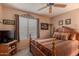 Neutral bedroom with a wooden frame bed, patterned bedspread, ceiling fan, and lots of decor at 15256 N 62Nd Ave, Glendale, AZ 85306