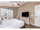 Bedroom features ceiling fan, dresser with TV, wood floors, and a sliding barn door to bathroom at 16365 N 138Th Ave, Surprise, AZ 85374