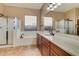 Bathroom featuring double sinks, a framed mirror, a tub, and a separate shower area at 16758 W Apache St, Goodyear, AZ 85338