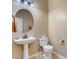 Powder room featuring pedestal sink, round mirror and toilet at 16758 W Apache St, Goodyear, AZ 85338
