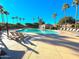 Resort-style community pool surrounded by palm trees and lounge chairs on a sunny day at 17864 W Fetlock Trl, Surprise, AZ 85387