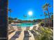 Inviting community pool lined with palm trees and lounge seating under a clear blue sky at 17864 W Fetlock Trl, Surprise, AZ 85387