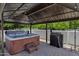 A clean, well-maintained hot tub sits under a metal gazebo next to a grill, perfect for outdoor relaxation and entertaining at 18132 E Vencino St, Gilbert, AZ 85298