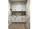 A laundry room with white cabinets, a granite countertop, and a farmhouse sink with wooden barn door at 18132 E Vencino St, Gilbert, AZ 85298