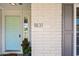 Front door with light blue paint, brick facade, and clear address numbers beside a colorful plant at 1831 W Seldon Ln, Phoenix, AZ 85021
