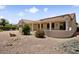 Backyard view featuring a covered patio, desert landscaping, and beautiful flowering bushes at 20007 N Siesta Rock Dr, Surprise, AZ 85374