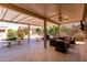 Relaxing covered patio with comfortable seating, ceiling fan, and view of landscaped backyard at 20223 N Sundance Way, Surprise, AZ 85374