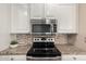 The kitchen boasts granite countertops, mosaic backsplash, and stainless appliances including microwave and oven at 20223 N Sundance Way, Surprise, AZ 85374