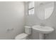 Cozy powder room featuring a pedestal sink, toilet, and round mirror over the sink at 2028 N 77Th Ln, Phoenix, AZ 85035