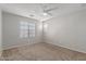 Bright carpeted bedroom with a ceiling fan and natural light from the windows at 2028 N 77Th Ln, Phoenix, AZ 85035