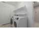 Laundry room featuring new white washer and dryer and shelving above at 2028 N 77Th Ln, Phoenix, AZ 85035