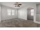 Inviting carpeted living room with large windows, a ceiling fan, and arched doorways at 2028 N 77Th Ln, Phoenix, AZ 85035