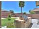 Outdoor kitchen with built-in grill overlooks a manicured lawn and mature landscaping at 22121 N Greenland Park Dr, Maricopa, AZ 85139