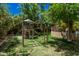 Lush backyard with play structure, grassy lawn, and mature trees, perfect for outdoor fun at 24348 S 201St Ct, Queen Creek, AZ 85142