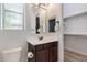 Bright bathroom with a single sink vanity, neutral paint, and a view of a walk-in closet at 24348 S 201St Ct, Queen Creek, AZ 85142