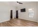 Bright bedroom featuring wood floors, a ceiling fan, and a flatscreen television at 24348 S 201St Ct, Queen Creek, AZ 85142