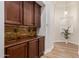 Hallway featuring wooden cabinetry, stone backsplash, and a decorative glass block window at 24348 S 201St Ct, Queen Creek, AZ 85142