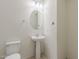 Cozy bathroom features a pedestal sink and toilet with a small round mirror at 27413 W Tonopah Dr, Buckeye, AZ 85396