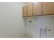 Functional laundry area equipped with overhead cabinets for storage and necessary utility connections at 27413 W Tonopah Dr, Buckeye, AZ 85396