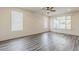 Bright, empty living room featuring modern wood-look floors, large windows, and a ceiling fan at 27413 W Tonopah Dr, Buckeye, AZ 85396