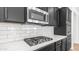 Close-up of kitchen showcasing stainless steel gas cooktop, microwave, white subway tile backsplash, and dark cabinets at 31653 N 24Th Dr, Phoenix, AZ 85085