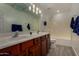 Bathroom featuring double sinks, white countertops, wood cabinets, and tiled shower and flooring at 34970 N Spur Cir, San Tan Valley, AZ 85144