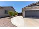 Wide driveway and parking area leading to garage, with gravel landscaping along the side of the house at 34970 N Spur Cir, San Tan Valley, AZ 85144