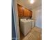 This laundry room includes tile flooring, wood cabinets, and a white washer and dryer at 351 S Apache Dr, Chandler, AZ 85224