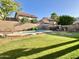 Backyard featuring a sparkling pool, lush green grass, and mature trees providing shade and privacy at 4002 E Agave Rd, Phoenix, AZ 85044