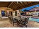 Backyard with outdoor dining near the pool, complete with a cozy fireplace and ambient string lights at 4610 E Meadowview Dr, Gilbert, AZ 85298