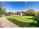 Large backyard with a putting green, pool, covered patio, and mature trees at 4610 E Meadowview Dr, Gilbert, AZ 85298