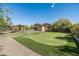 Spacious backyard featuring a putting green, pool, and covered patio with lush landscaping at 4610 E Meadowview Dr, Gilbert, AZ 85298
