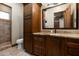 Bathroom with a tiled shower, tan granite countertops, and dark wood cabinets for a luxurious feel at 4610 E Meadowview Dr, Gilbert, AZ 85298