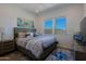 Comfortable bedroom featuring a queen bed with stylish linens, vibrant artwork, and natural light from two windows at 5614 W Saint Moritz Ln, Glendale, AZ 85306