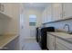 This large laundry room provides ample counter space, upper and lower cabinets and a sink next to front loading machines at 5614 W Saint Moritz Ln, Glendale, AZ 85306