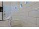Bright, modern shower showcasing sleek, large white tiles, a built-in bench, and black and white patterned floor at 5614 W Saint Moritz Ln, Glendale, AZ 85306
