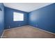 This bedroom has blue walls, tan carpet, and a window for natural light at 6128 W Columbine Dr, Glendale, AZ 85304