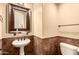 Convenient powder room featuring pedestal sink, framed mirror, and tiled wainscotting at 7134 E Sandia St, Mesa, AZ 85207