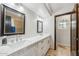 Bathroom featuring dual sinks, white cabinets, decorative mirror and a separate tiled shower at 7214 E Royal Palm Rd, Scottsdale, AZ 85258