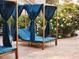 Inviting outdoor cabana lounge area with blue cushions and privacy curtains, nestled amongst flowering plants at 7214 E Royal Palm Rd, Scottsdale, AZ 85258