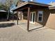 Covered outdoor patio with gravel, brown posts and support beams, and french doors at 8117 W Dreyfus Dr, Peoria, AZ 85381