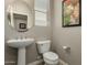 Stylish half bathroom with a pedestal sink, round mirror and modern fixtures at 9747 W Sands Dr, Peoria, AZ 85383
